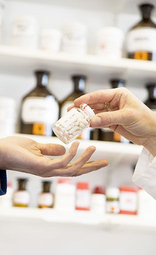 Ldos. Alzamora – Buiza Farmacia - Farmacéutico dando Frasco de pastillas a cliente